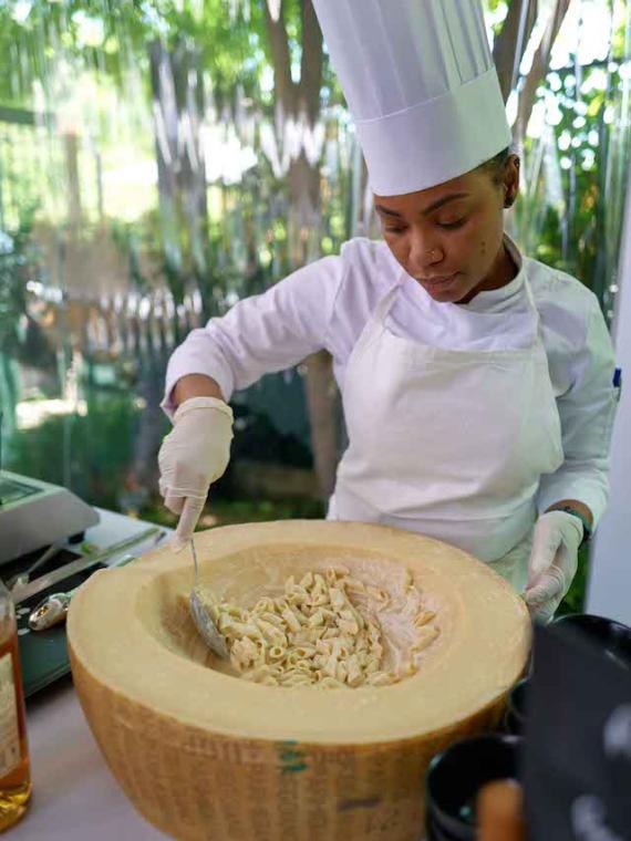 Un chef cuisiner prépare des pates à l'italienne dans meule de parmesan au Pavillon Roland-Garros