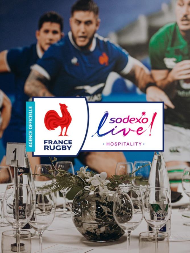 Une table d'un espace hospitalité premium avec en fonds un match de rugby